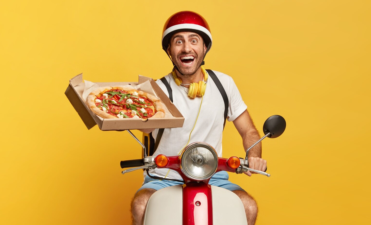 Pizzakurier mit Helm und geöffnetem Pizzakarton vor gelbem Hintergrund